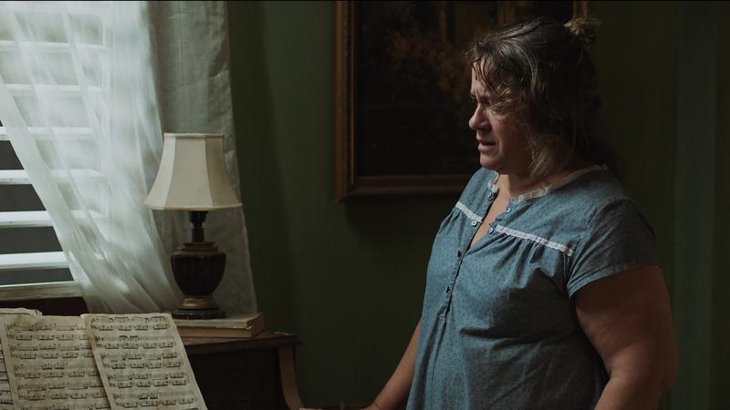 Abril stands alone beside the piano and its sheet music