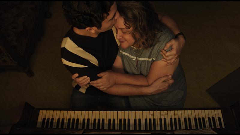 Seen from above, Cristóbal embraces his mother over the piano keys